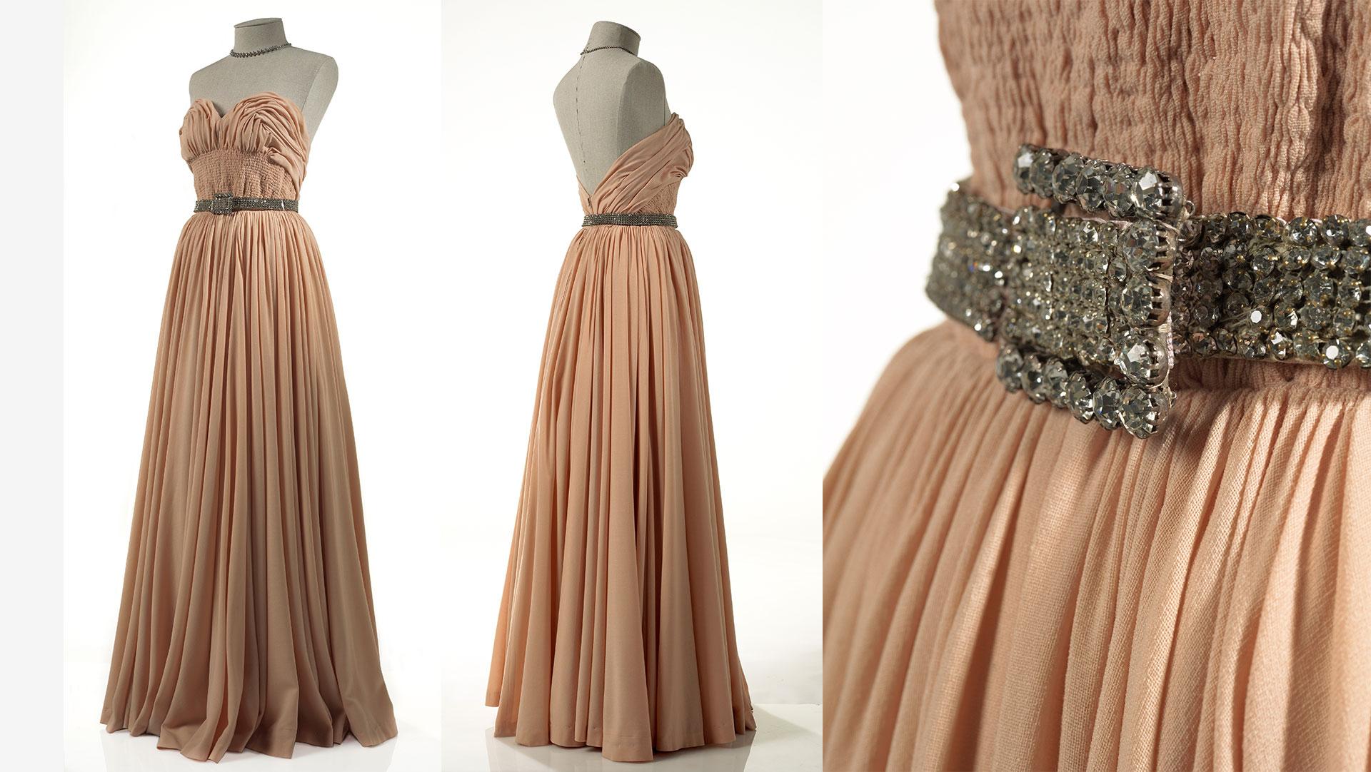 A pale shell pink evening gown by Pierre Balmain from 1949. The fine wool mousse line gown featured a full skirt measuring 20 yards around the hemline, and a twinkling 'touch of Paris' at the waistline. Collection of Te Papa.
